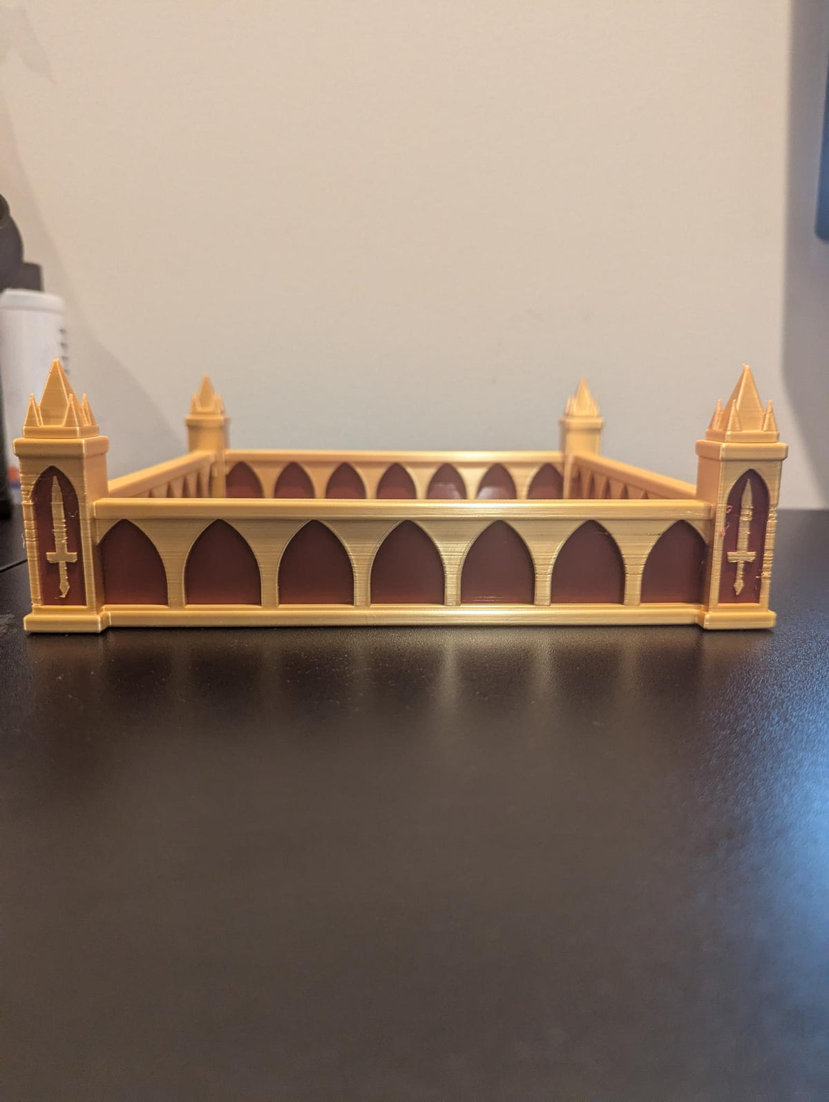 Straight-on front view of the pointed-arch wall and sword-emblem towers